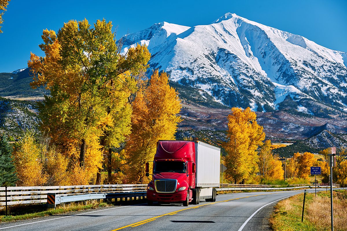 Red truck on highway near mountains during autumn